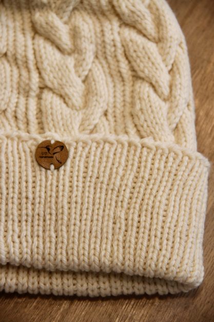 Strickmütze Beige Strickmütze mit Zopfmuster und braunem Label.
